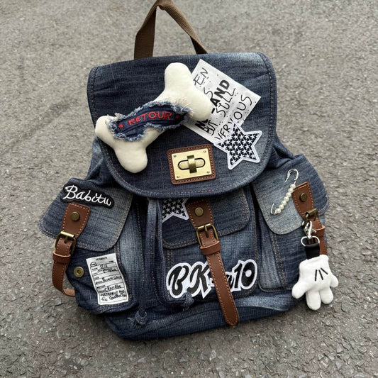 Denim backpack with patches and decorative items on a concrete surface
