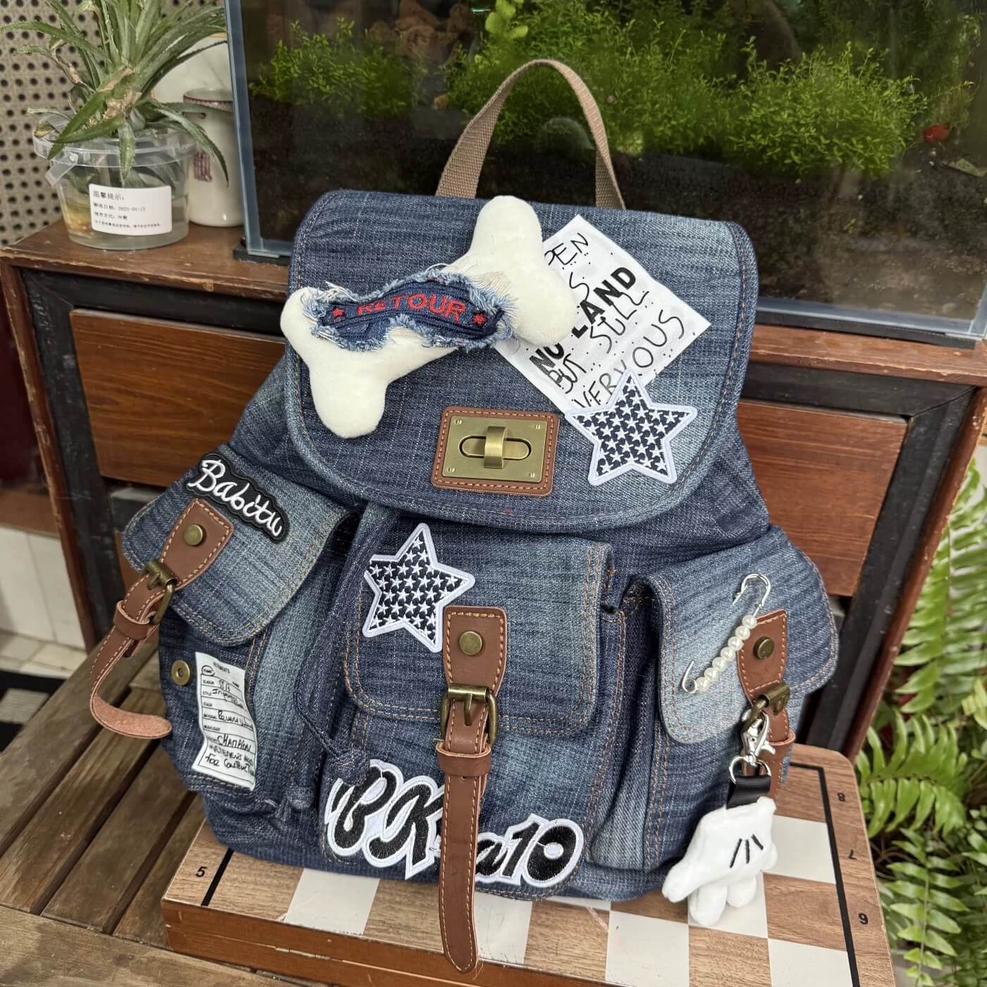 Denim backpack with patches and dog toys on a wooden surface