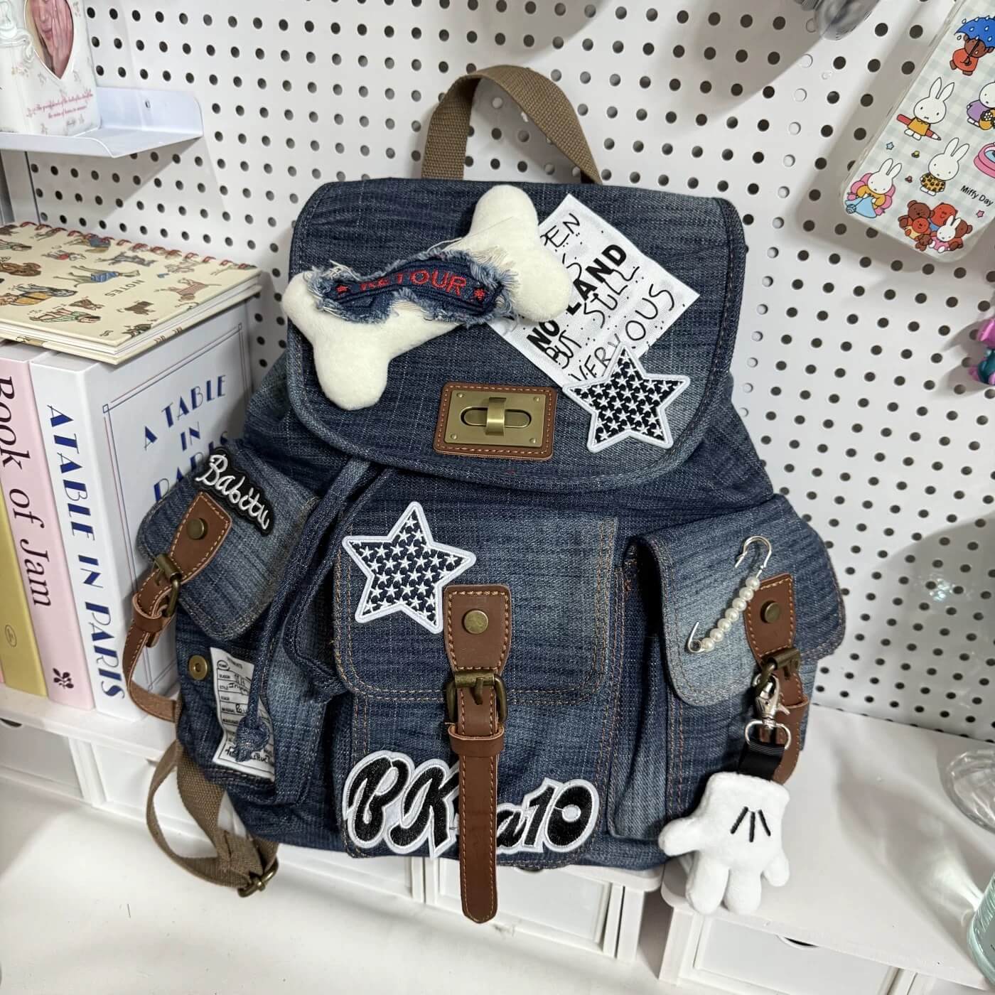 Denim backpack with patches and a bone-shaped toy on a shelf.