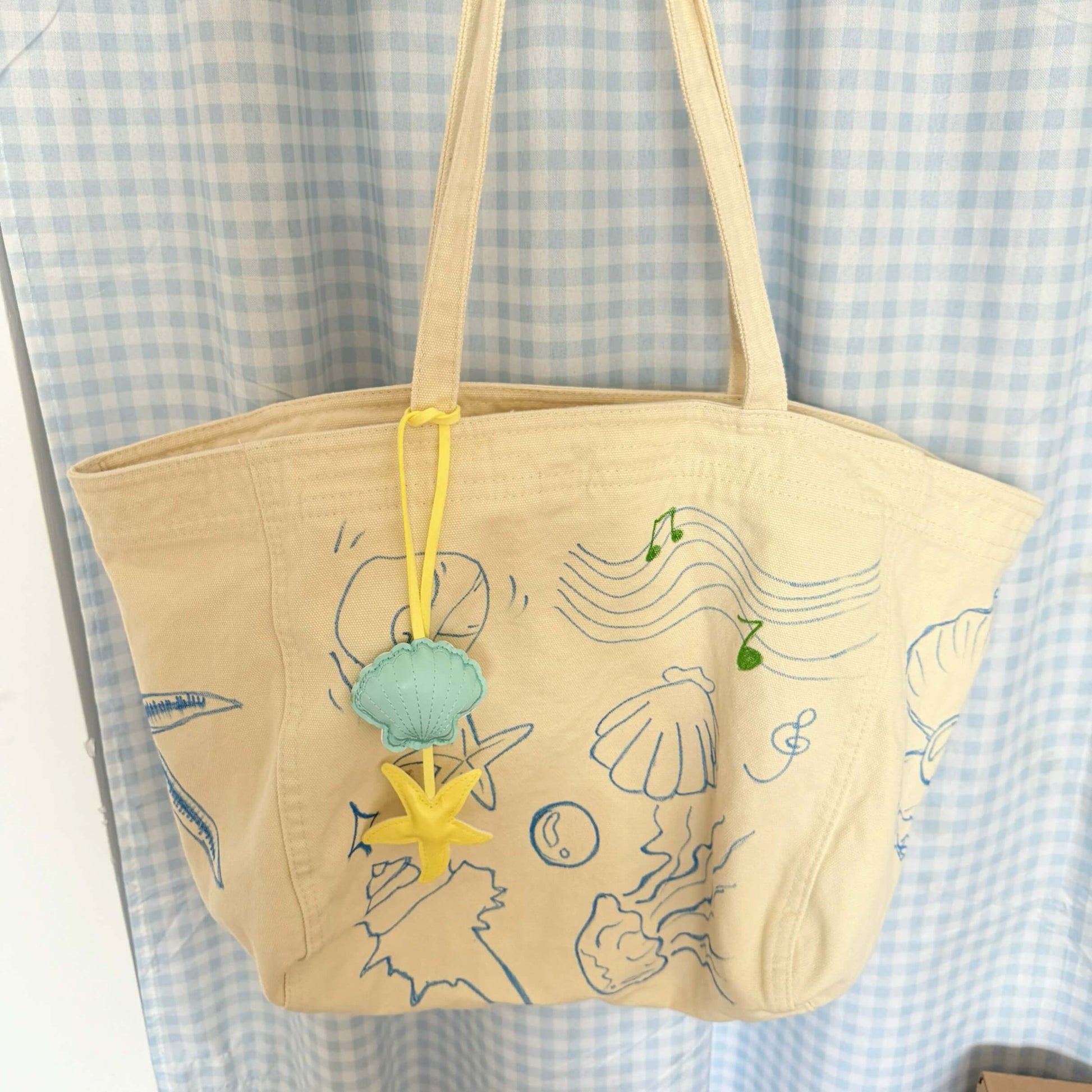 Beige tote bag with sea-themed designs on a checkered fabric background