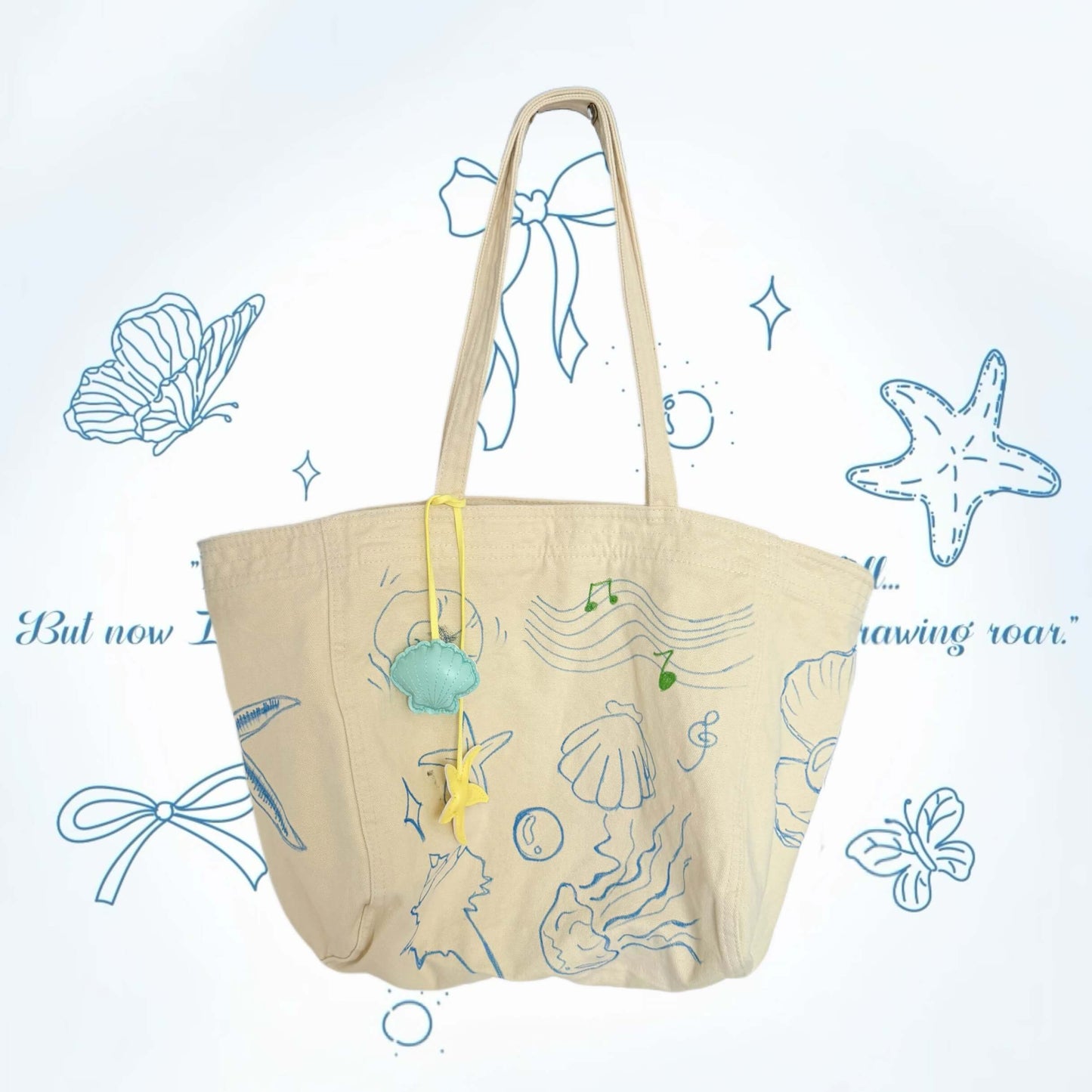 Beige tote bag with sea-themed illustrations on a light blue background with decorative elements.