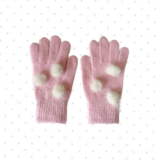 Soft pink knit gloves with white fuzzy pom poms for kawaii winter fashion.