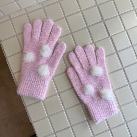 Soft pink knit gloves with white fuzzy pom poms for kawaii winter fashion.