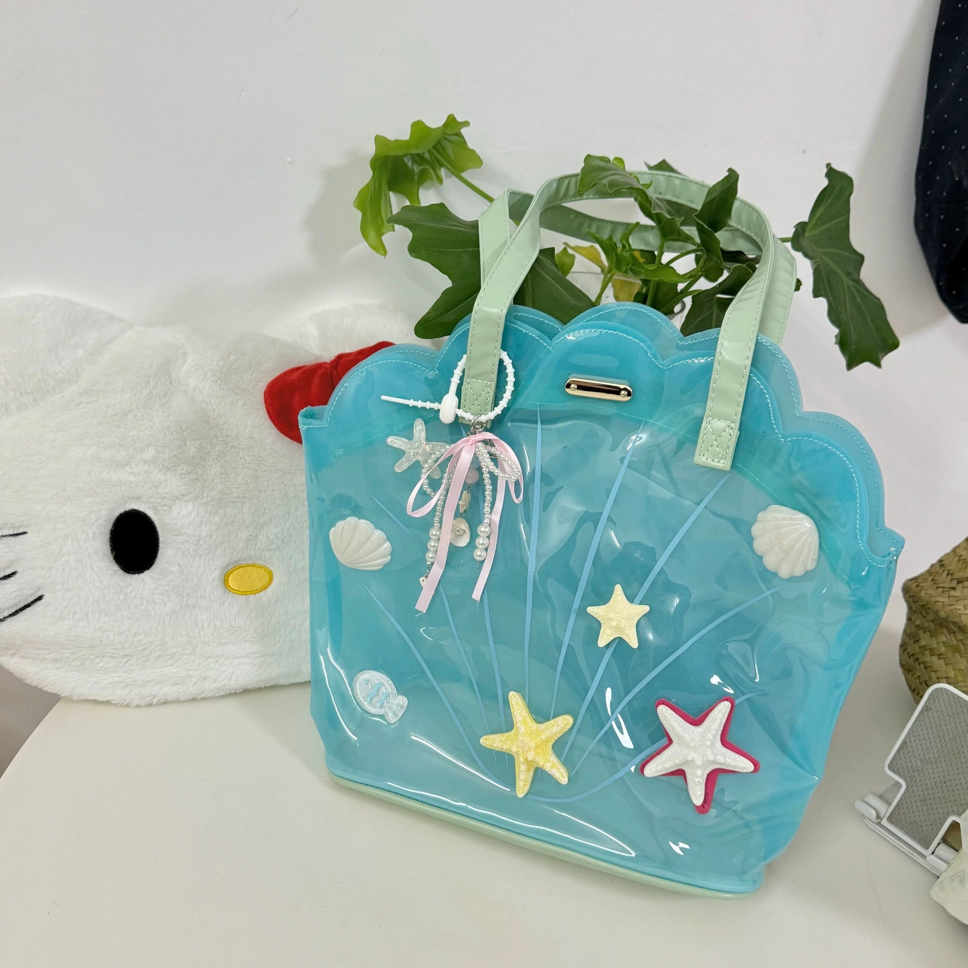 Clear aqua blue shell-shaped jelly tote bag with 3D starfish, seashells, and pearl ribbon charm.