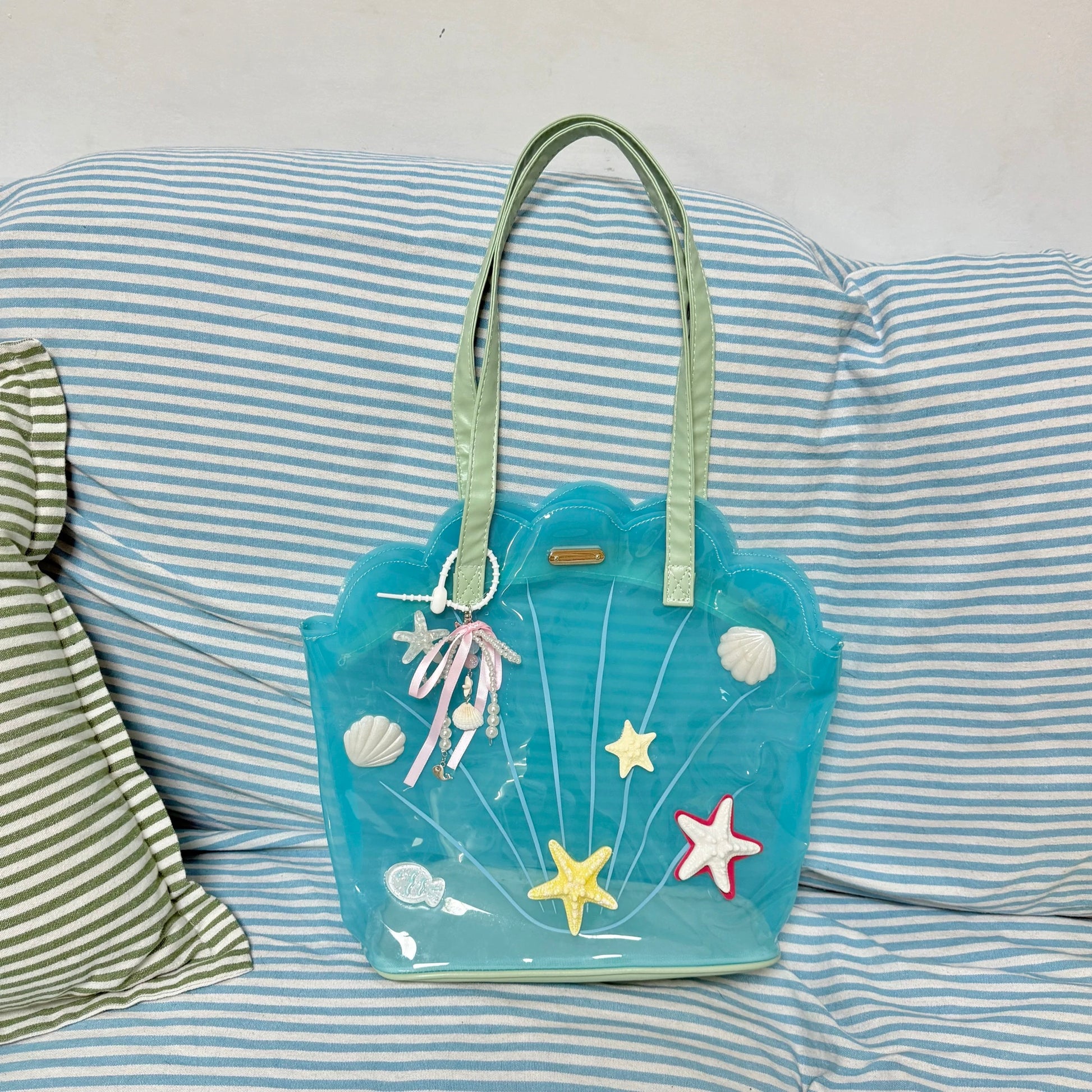 Clear aqua blue shell-shaped jelly tote bag with 3D starfish, seashells, and pearl ribbon charm.