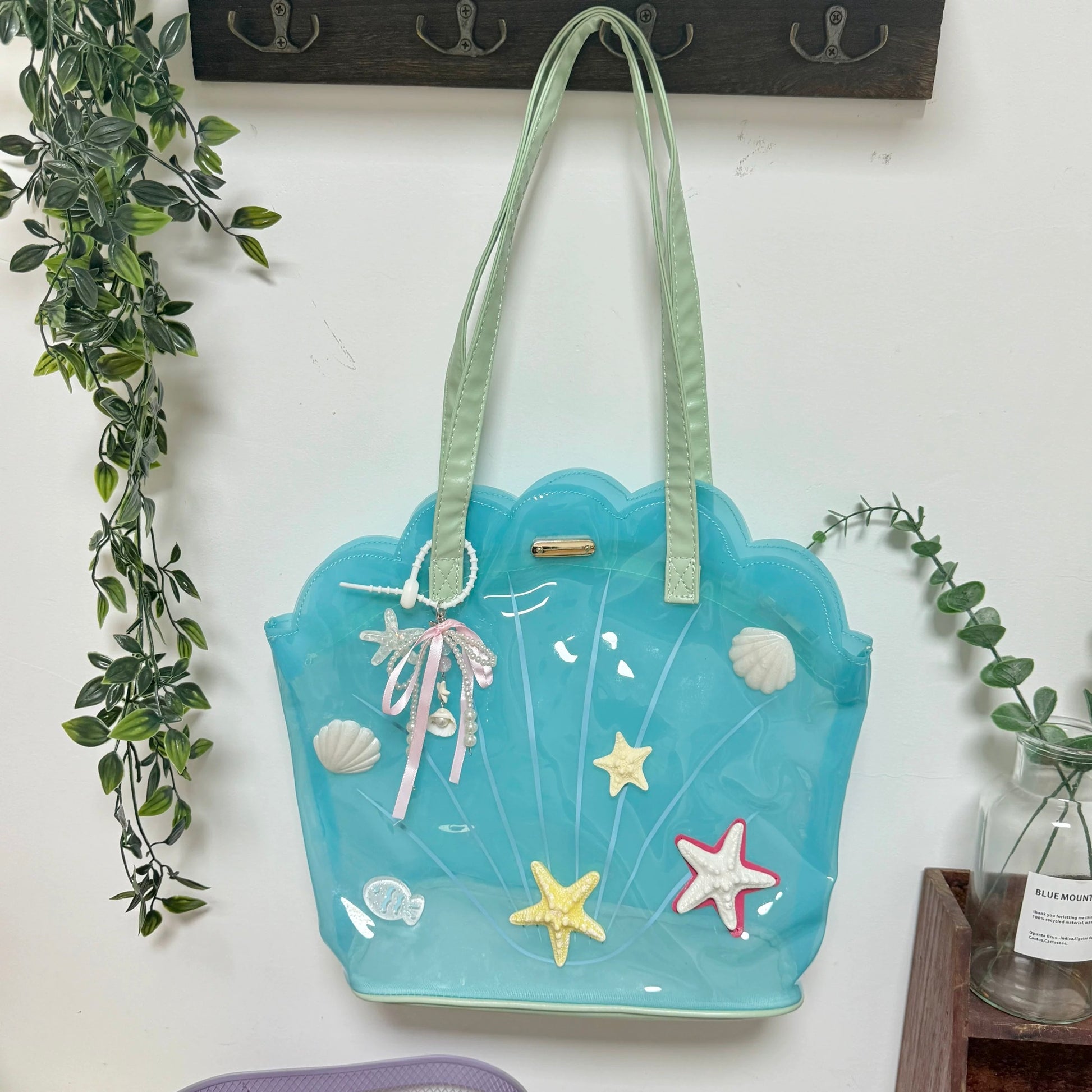 Clear aqua blue shell-shaped jelly tote bag with 3D starfish, seashells, and pearl ribbon charm.