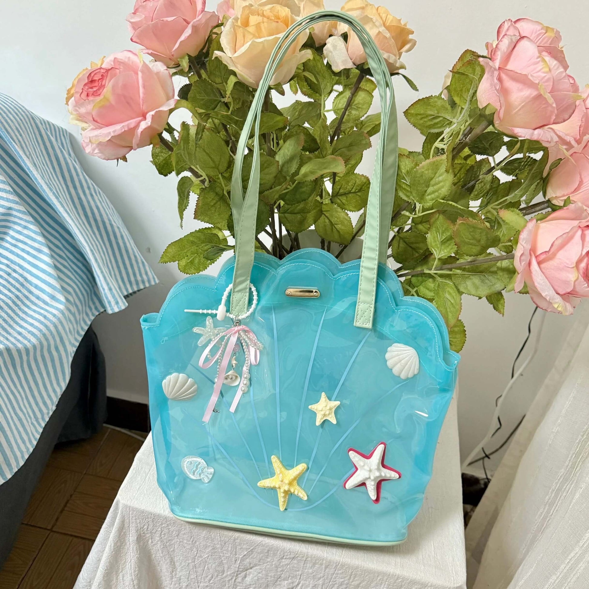 Clear aqua blue shell-shaped jelly tote bag with 3D starfish, seashells, and pearl ribbon charm.