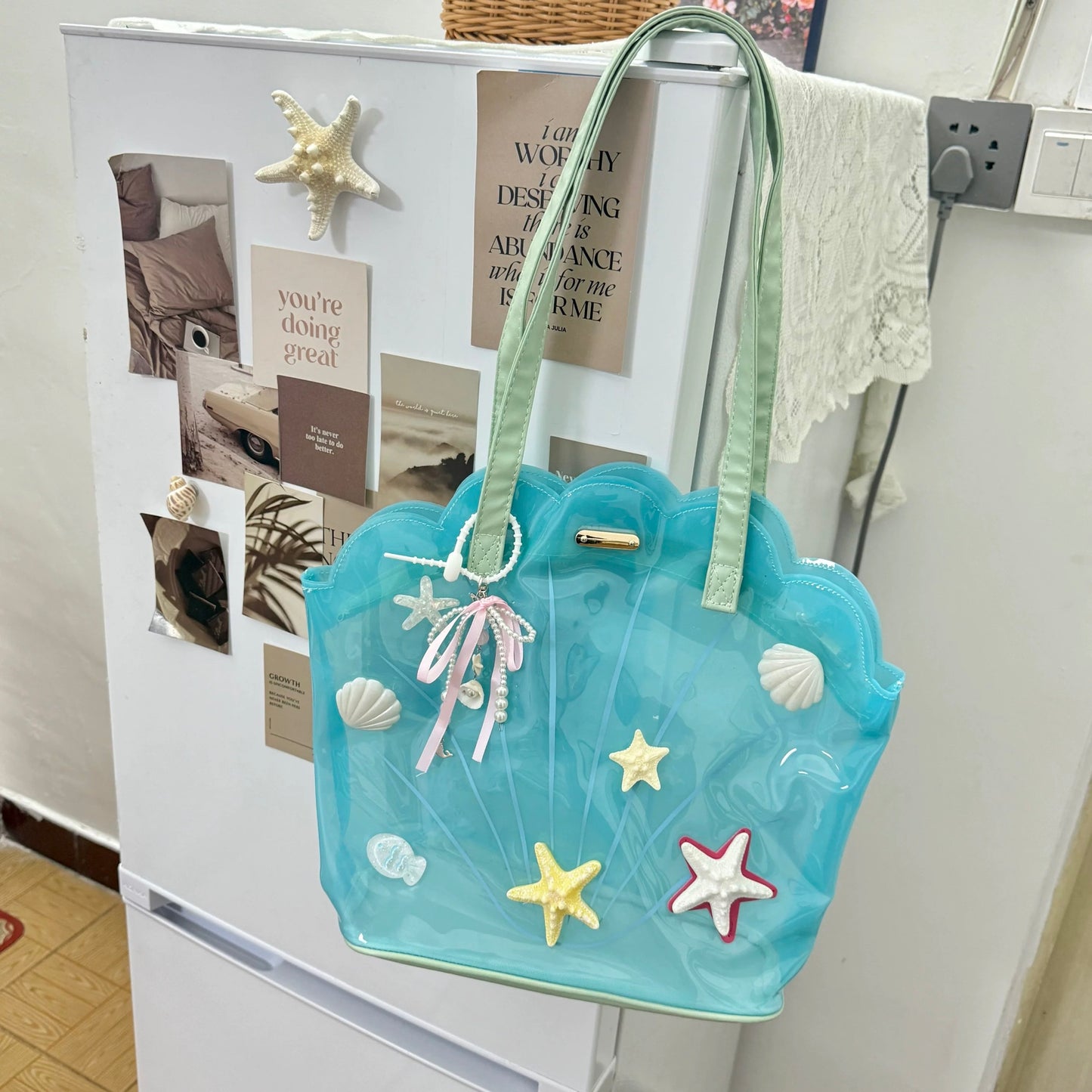 Clear aqua blue shell-shaped jelly tote bag with 3D starfish, seashells, and pearl ribbon charm.