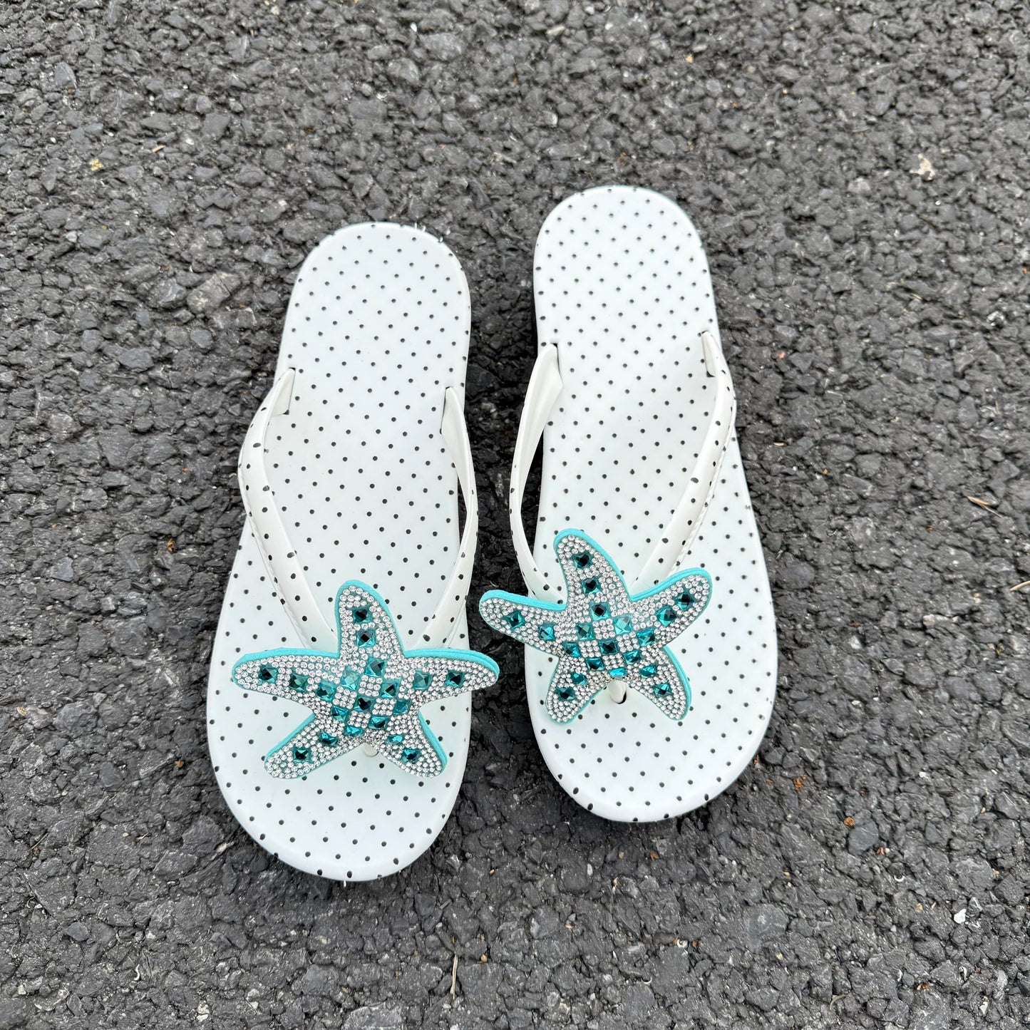 White polka dot flip flops with large jeweled turquoise starfish on sand