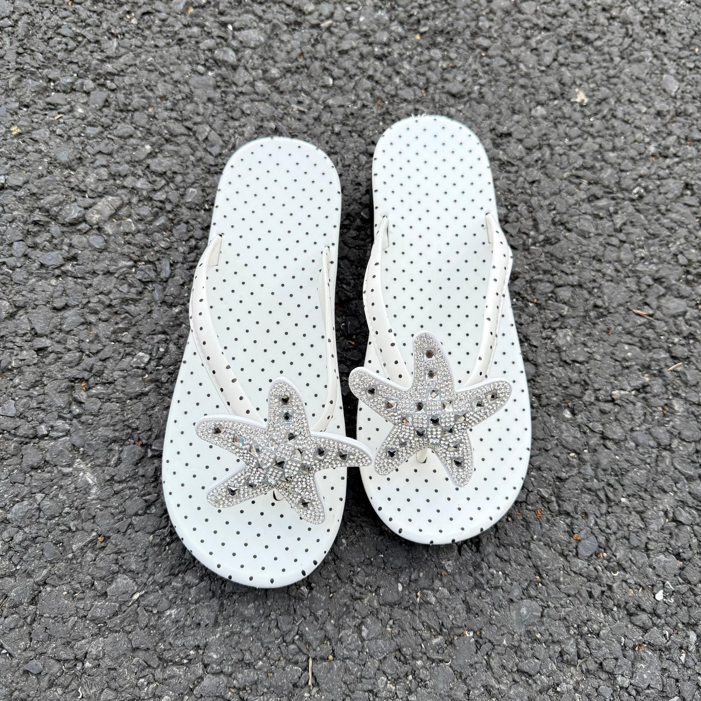 White polka dot flip flops with large jeweled turquoise starfish on sand