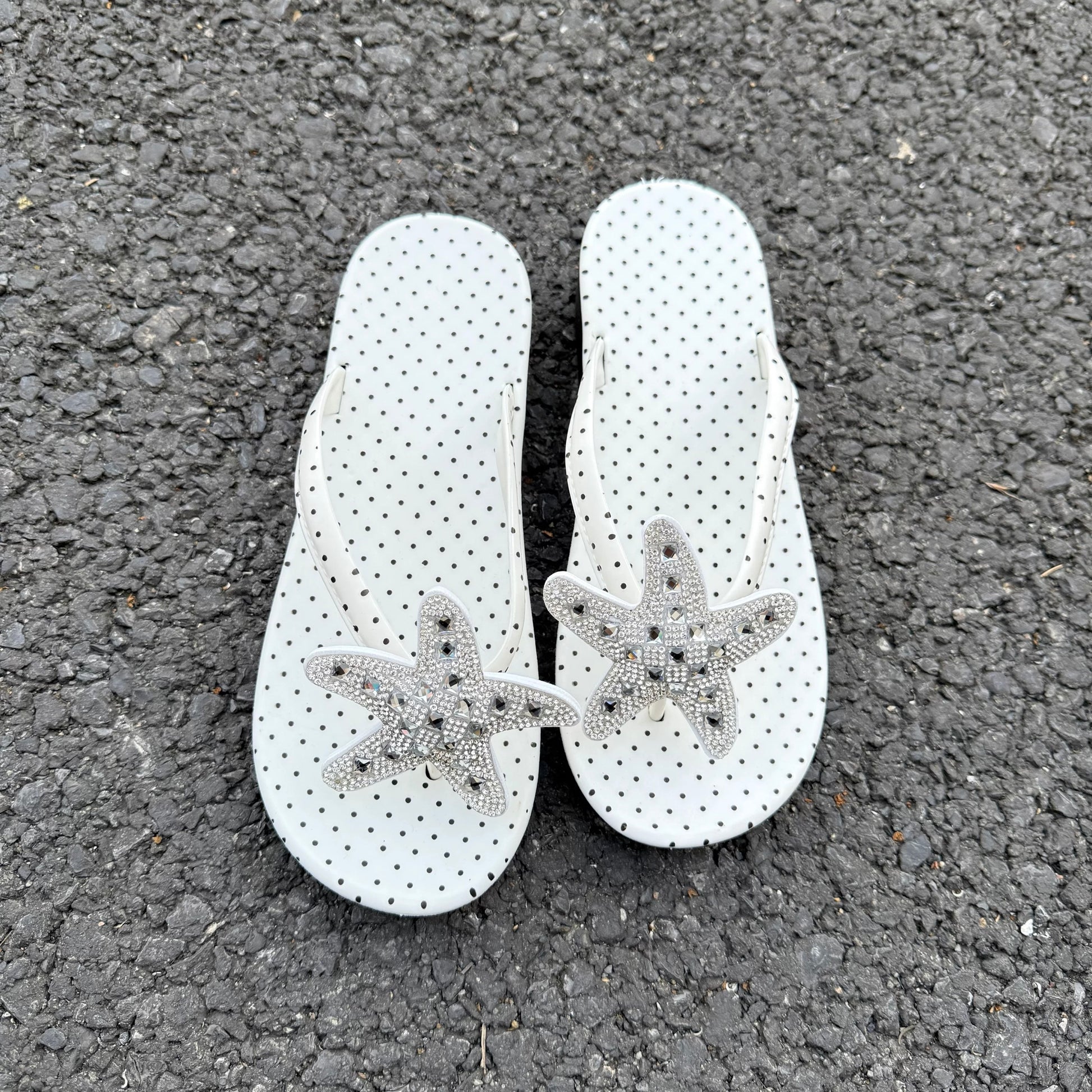 White polka dot flip flops with large jeweled turquoise starfish on sand