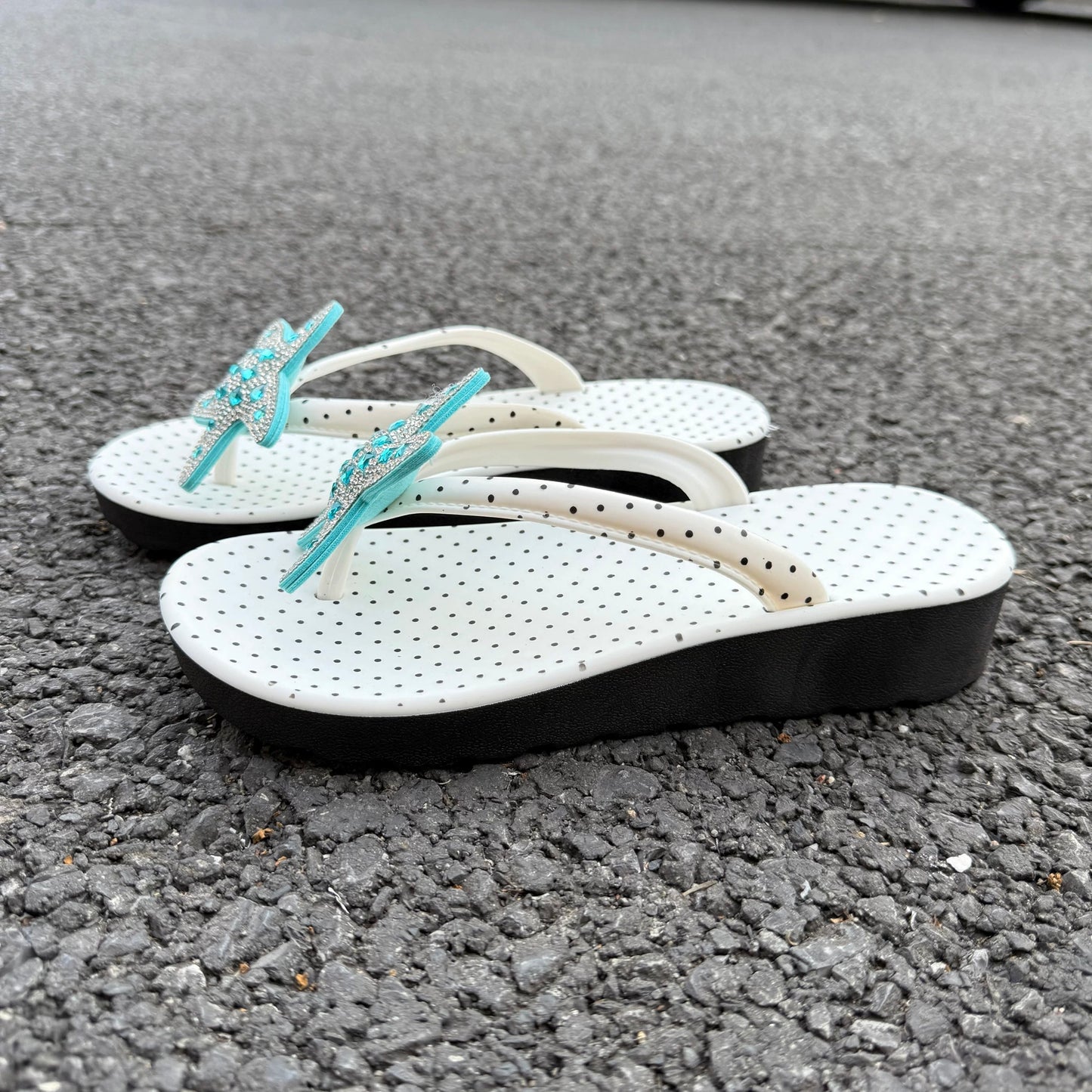 White polka dot flip flops with large jeweled turquoise starfish on sand