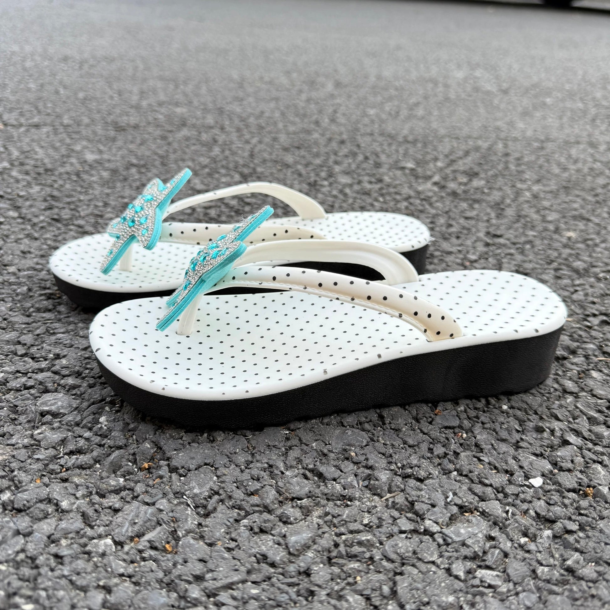 White polka dot flip flops with large jeweled turquoise starfish on sand