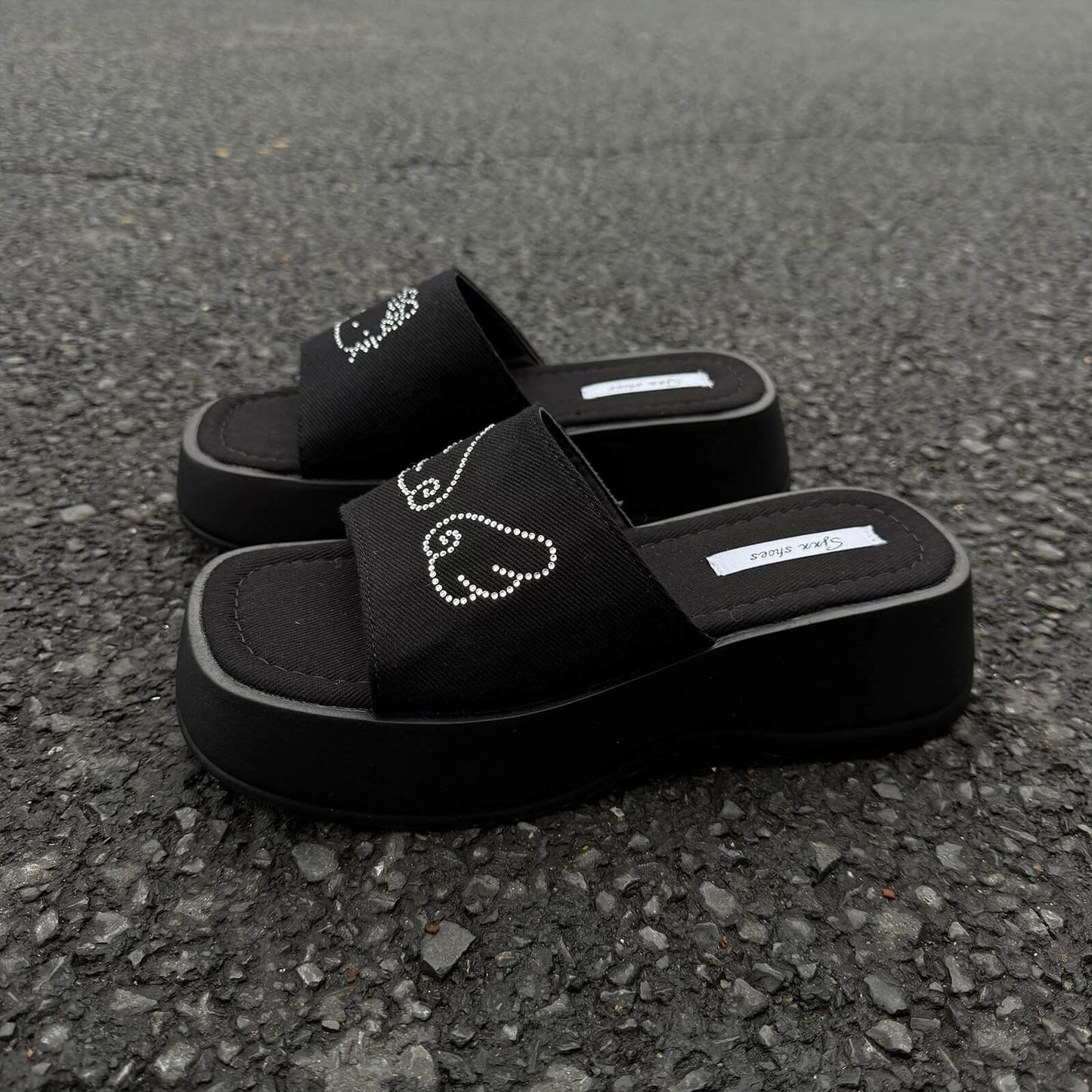 Black platform slide sandals with rhinestone cartoon cat design and chunky sole