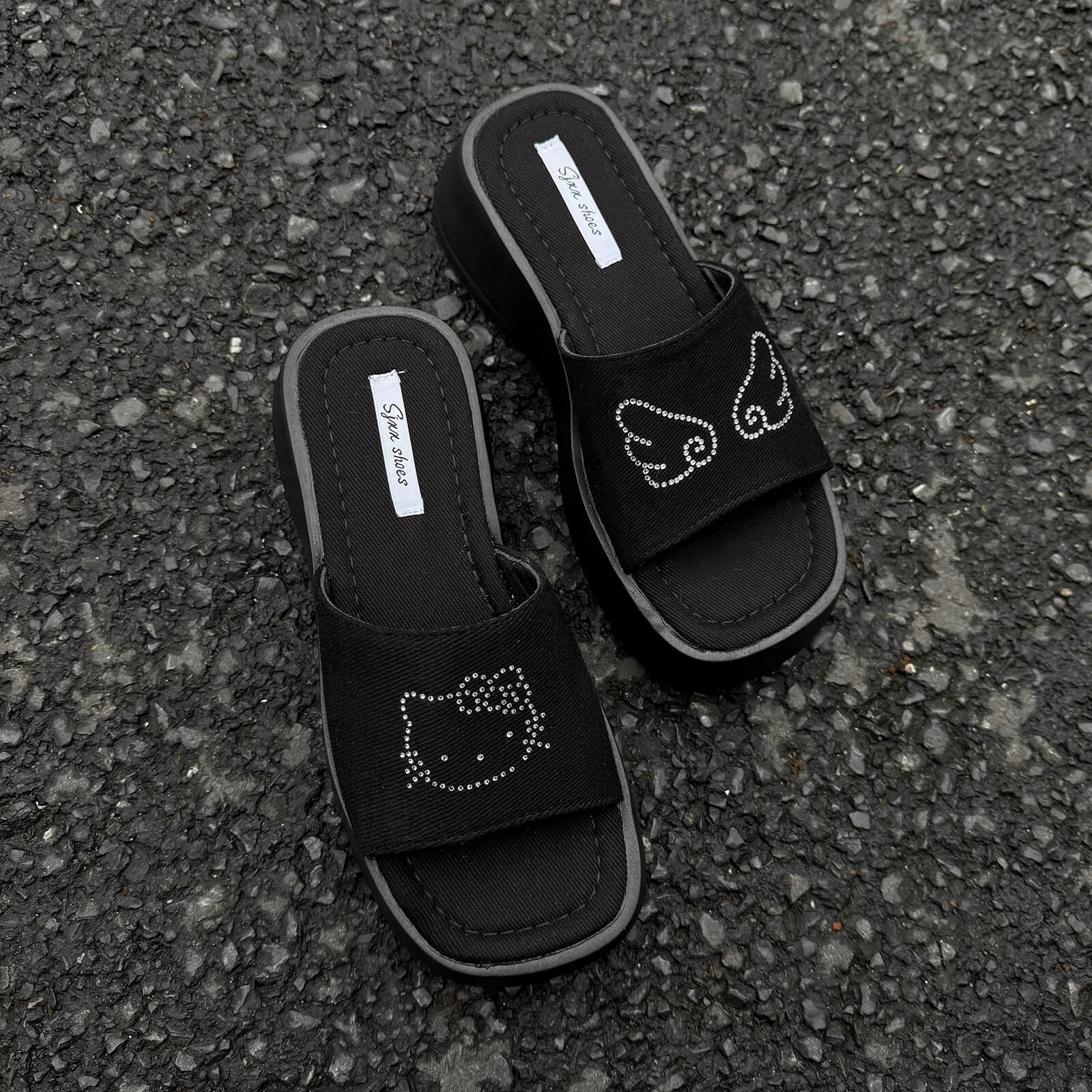 Black platform slide sandals with rhinestone cartoon cat design and chunky sole