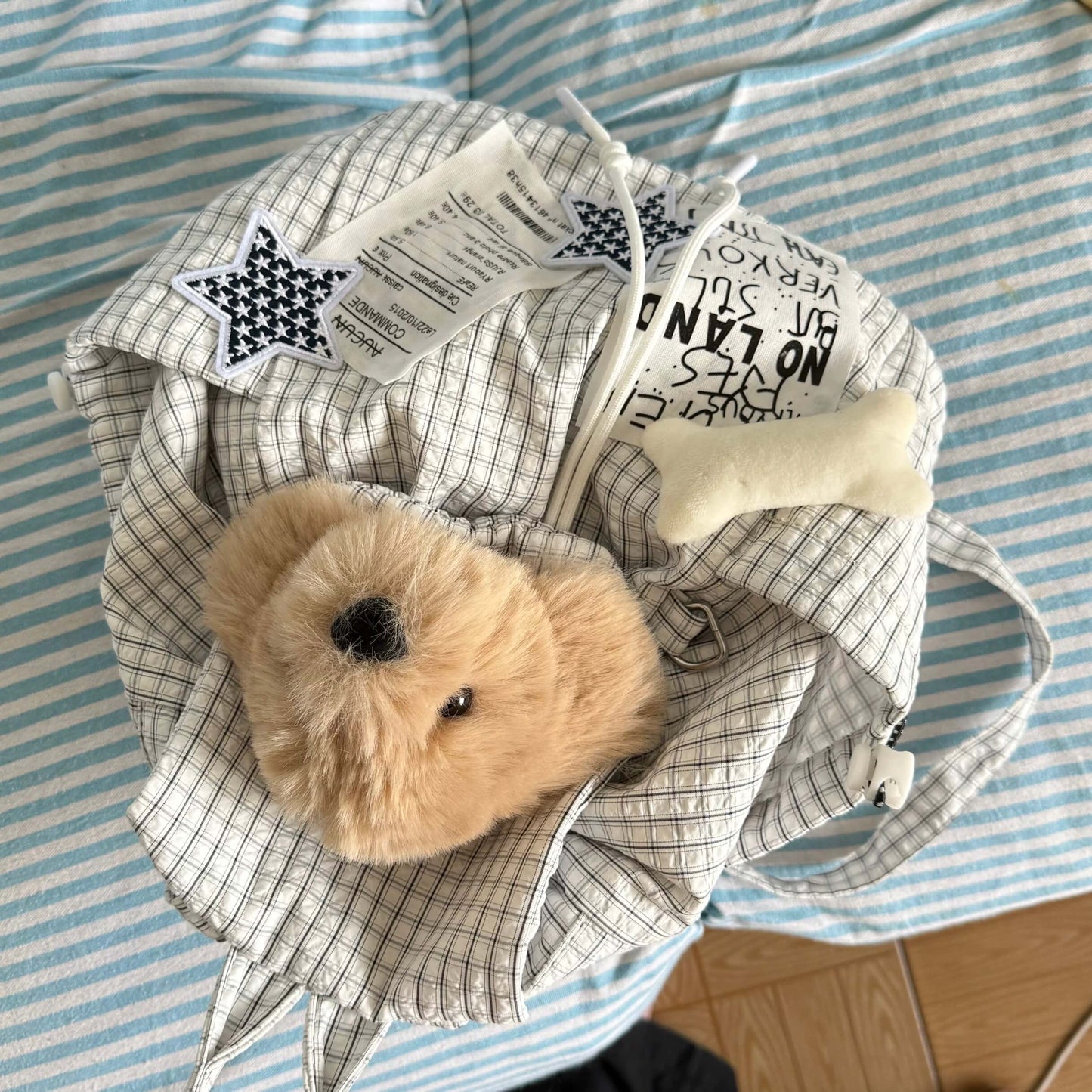 Small teddy bear inside a crumpled piece of paper with text on a striped fabric background