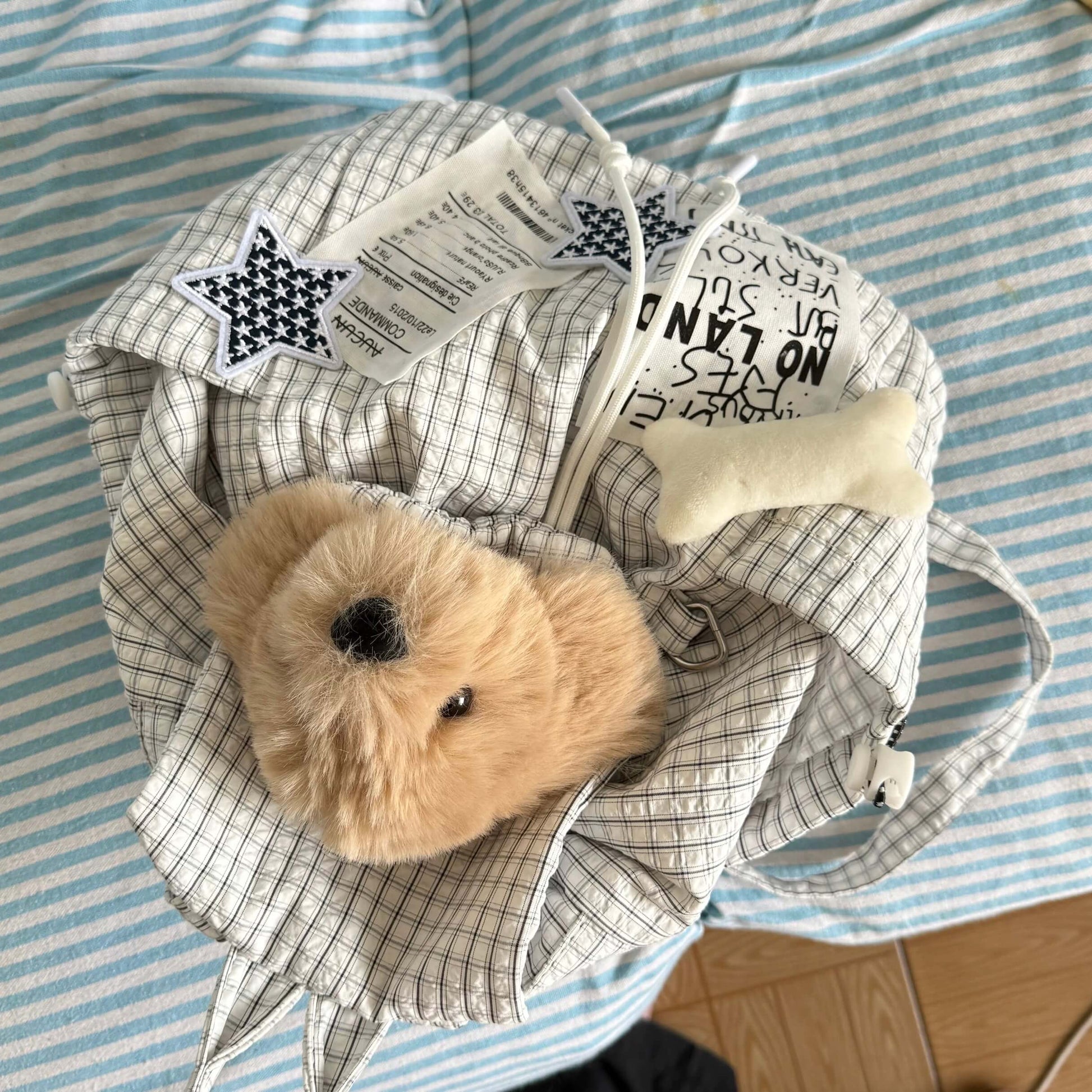 Small teddy bear inside a crumpled piece of paper with text on a striped fabric background