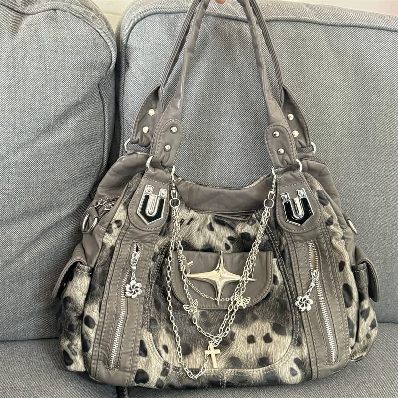 Gray handbag with animal print accents and decorative chains on a gray couch.