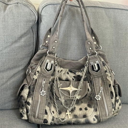 Gray handbag with animal print accents and decorative chains on a gray couch.