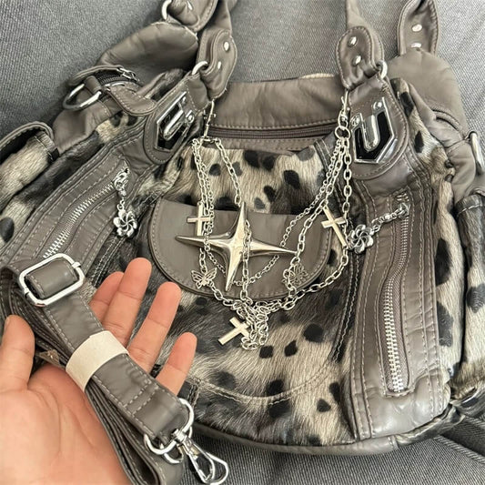 Gray leather bag with chain and star accessory held by a hand