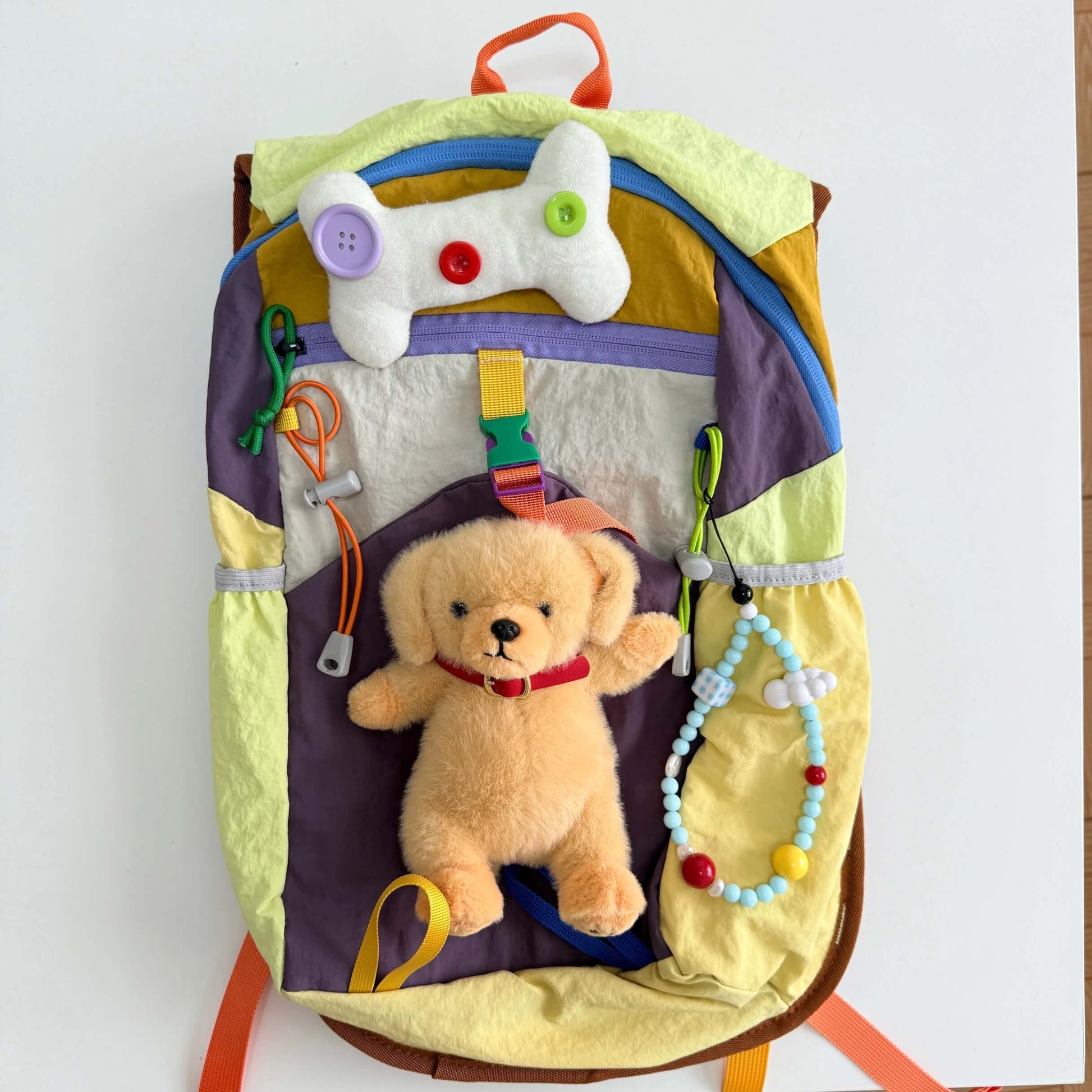 Colorful baby activity center with toys and a teddy bear on a white background